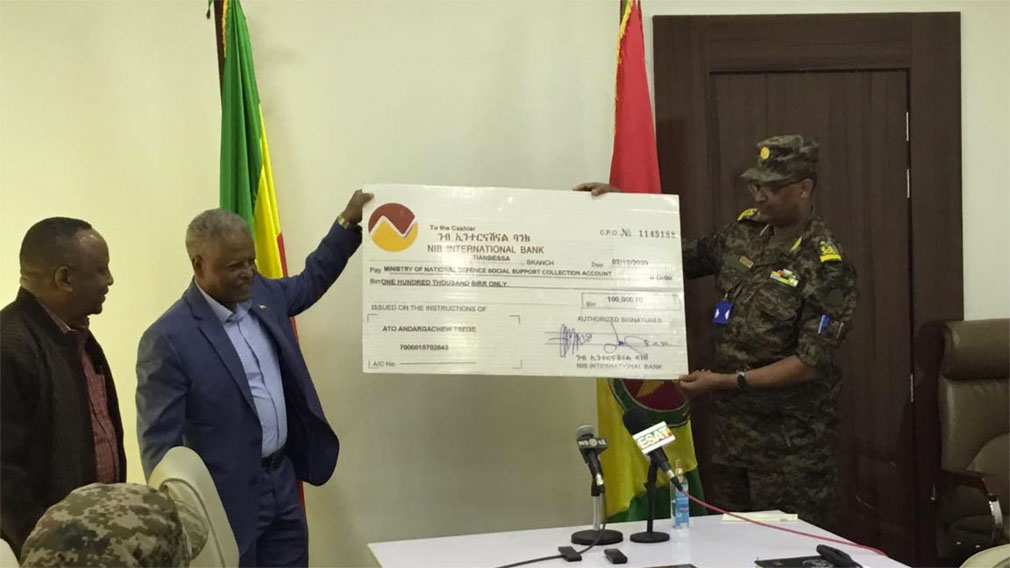 ፖለቲከኛ እና ደራሲ አንዳርጋቸው ጽጌ የመቶ ሺህ ብር ቼክ ለመከላከያ ውጭ ግንኙነት ዋና ዳይሬክቶሬት ዳይሬክተር ብርጋዲየር ጄኔራል ቡልቲ ሲያስረክቡ