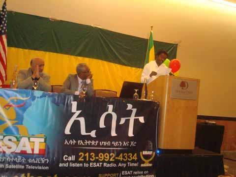 ወጣት ሄኖክ የሼጥላ ግጥሙን ለታዳሚዎች ሲያሰማ (ከግራ ወደ ቀኝ ሃጄ ነጂብ መሃመድ እና አርቲስት ታማኝ በየነ)