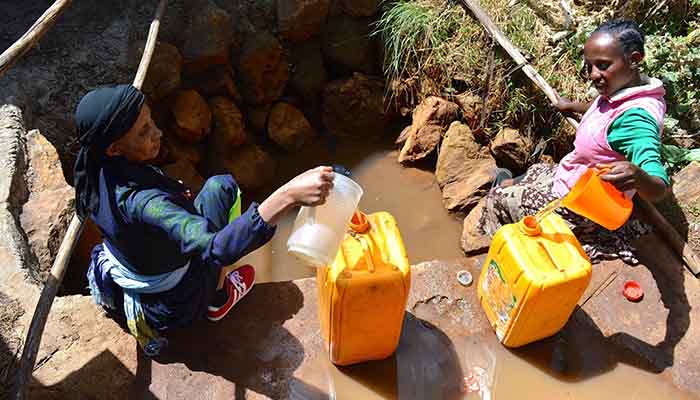Women collect water from a muddy well in Sululta.